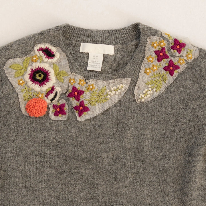 Gray sweater with floral embellishments on a white background