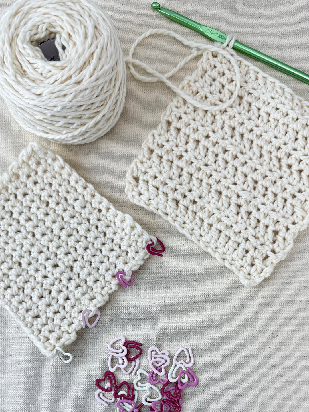Pink heart shaped stitch markers being used on a crochet project.
