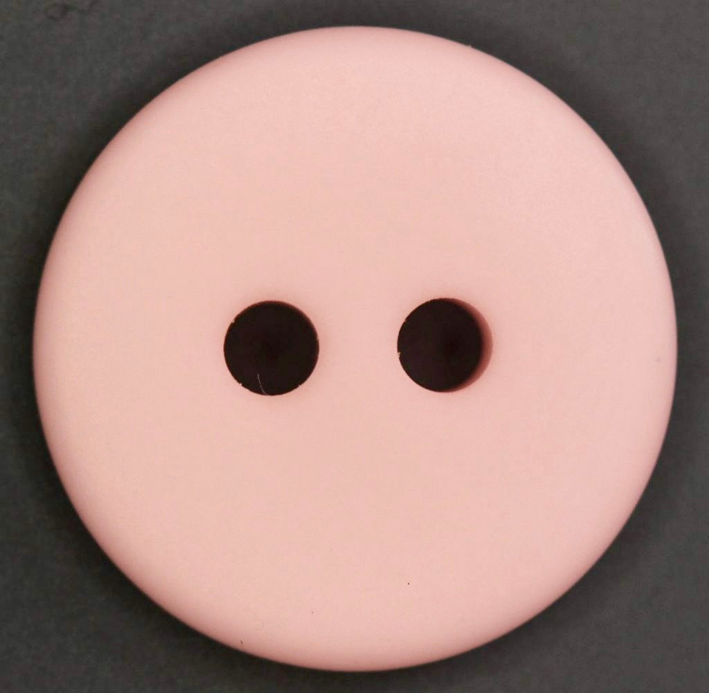Pink button with two holes on a dark background