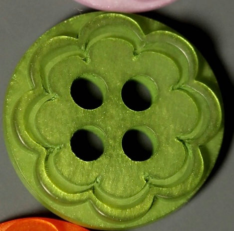 Green decorative button with a floral pattern on a gray background
