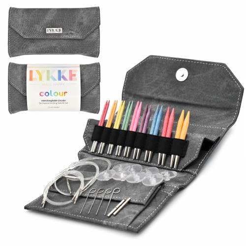 A set of interchangeable circular knitting needles with various colored tips, laid out in an open grey denim case. The set includes cords and connectors for different needle lengths.