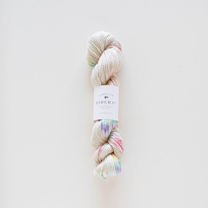 A skein of multicolored yarn with a label in the center, on a light background.