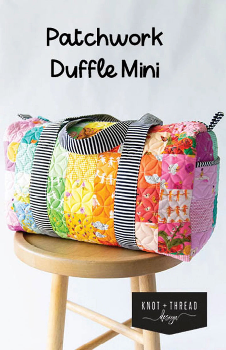 A multicolored patchwork duffle mini bag displayed on a wooden stool.