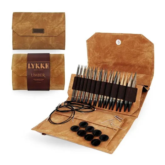 A set of interchangeable circular birchwood knitting needles in various sizes, displayed in an open denim-effect case with the brand name 'LYKKE UMBER' visible on the cover.