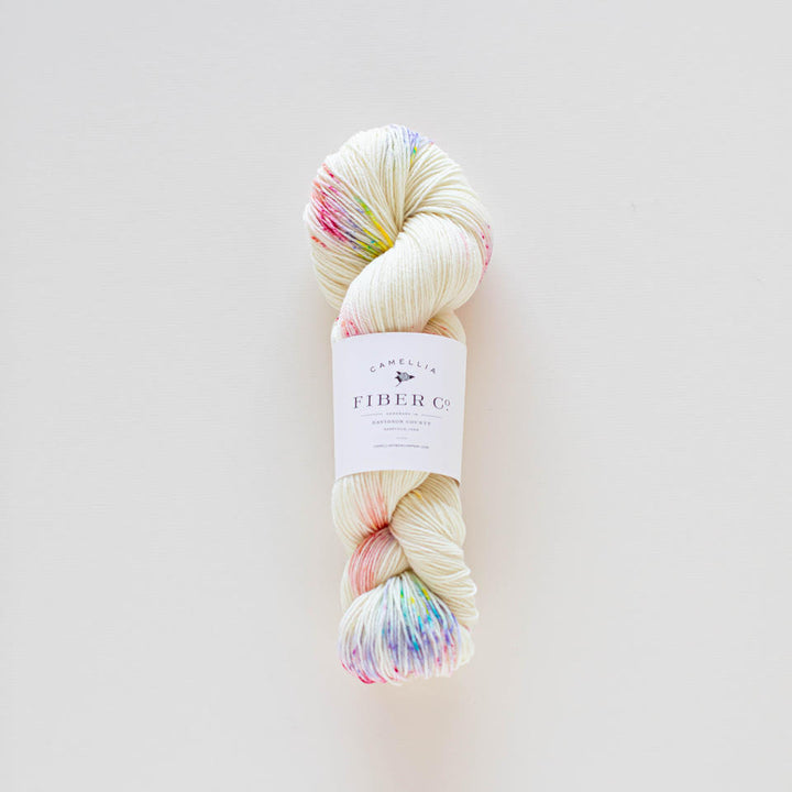 A skein of multicolored yarn with a label in the center, on a light background.