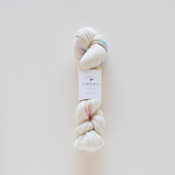 A skein of multicolored yarn with a label in the center, on a light background.