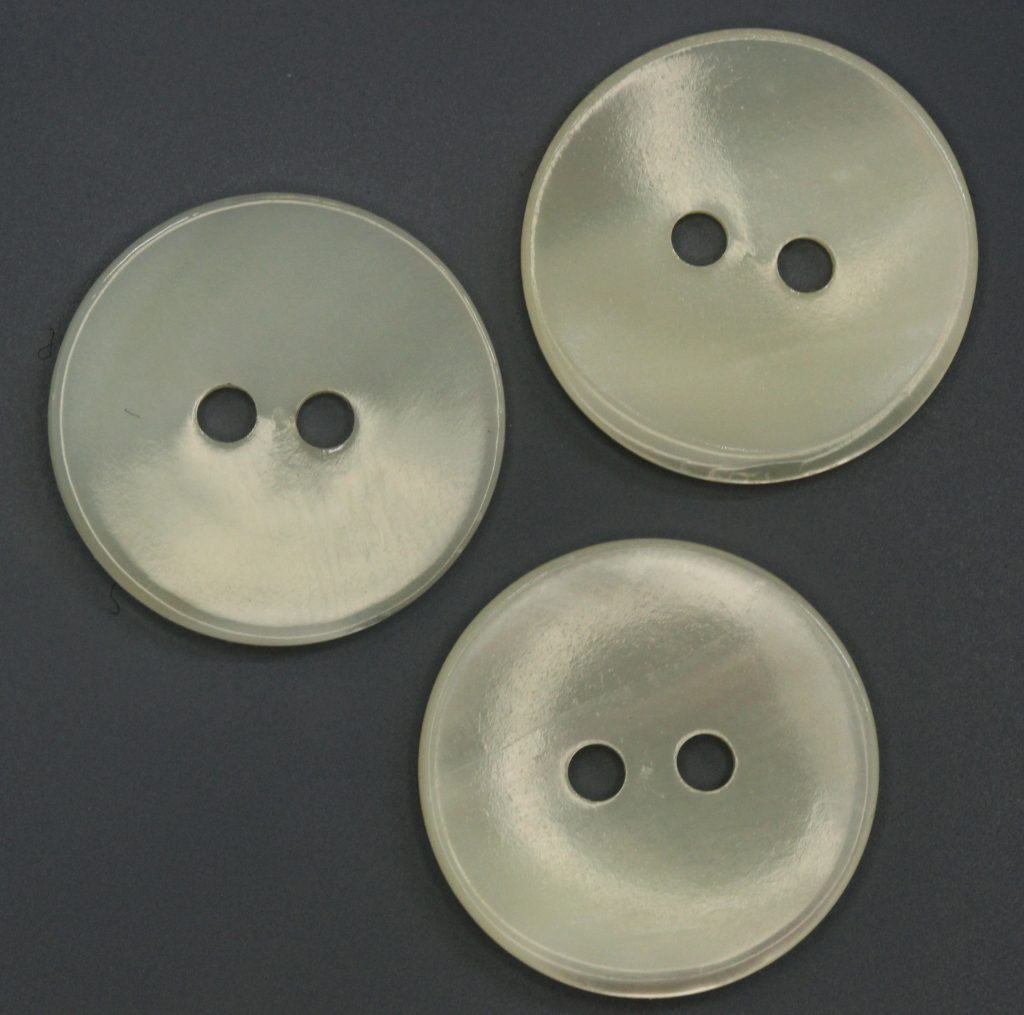 three 2-hole pearl buttons on a grey background