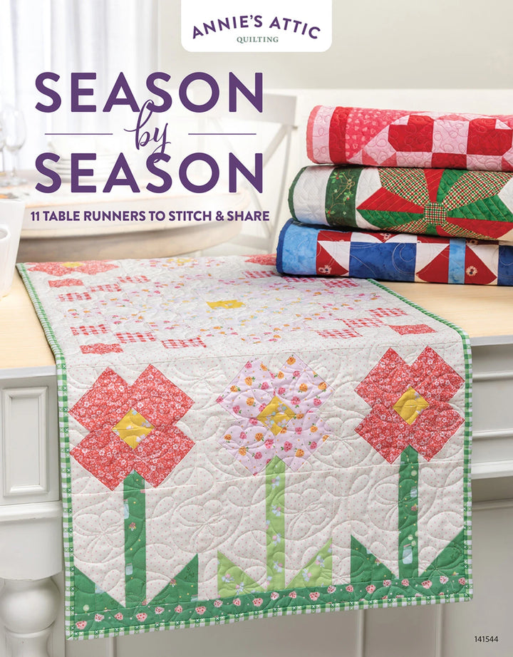 Quilted table runner with floral design on a wooden surface, featuring 'Annie's Attic' branding.
