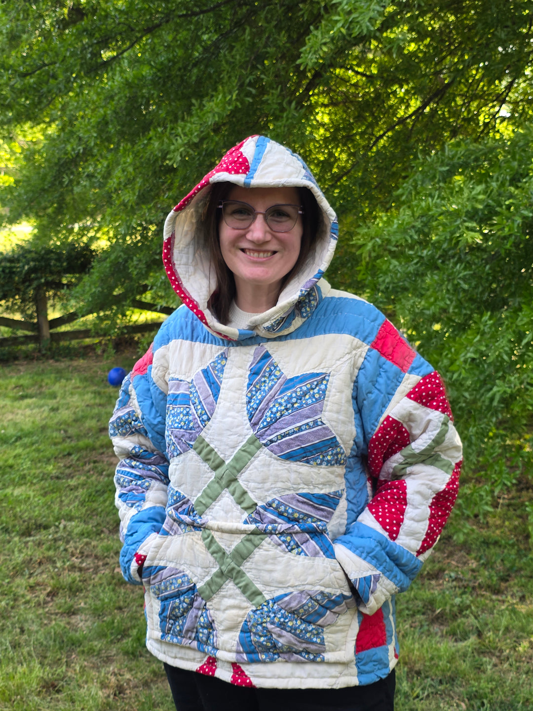 Person wearing a colorful quilted jacket outdoors with trees in the background