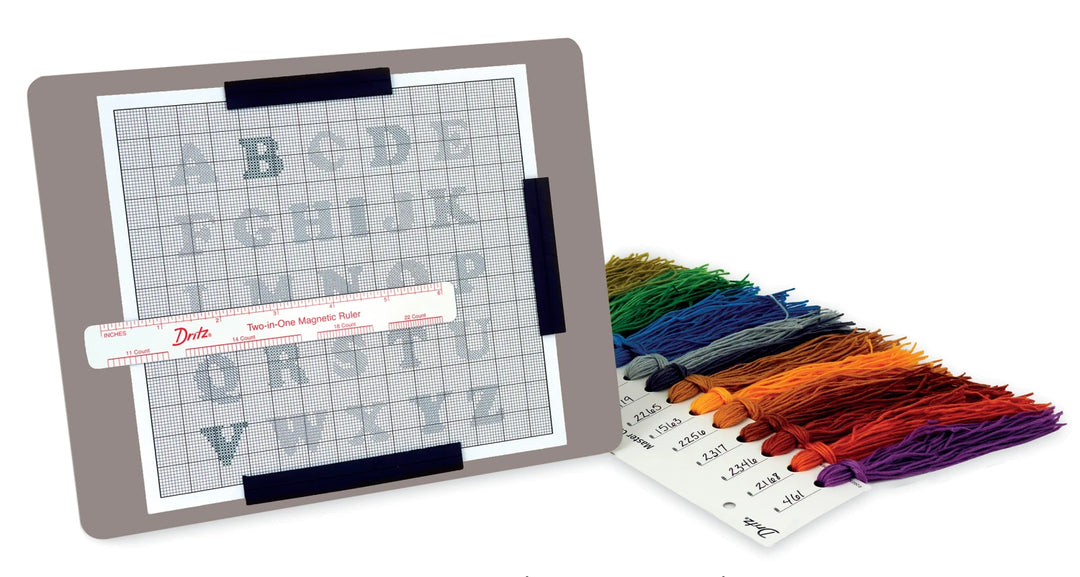 Embroidery magnet board with grid paper, color swatch, and thread on a white background