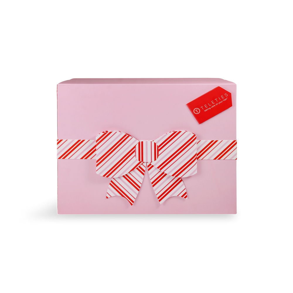 Pink gift box with a red and white striped bow on a white background