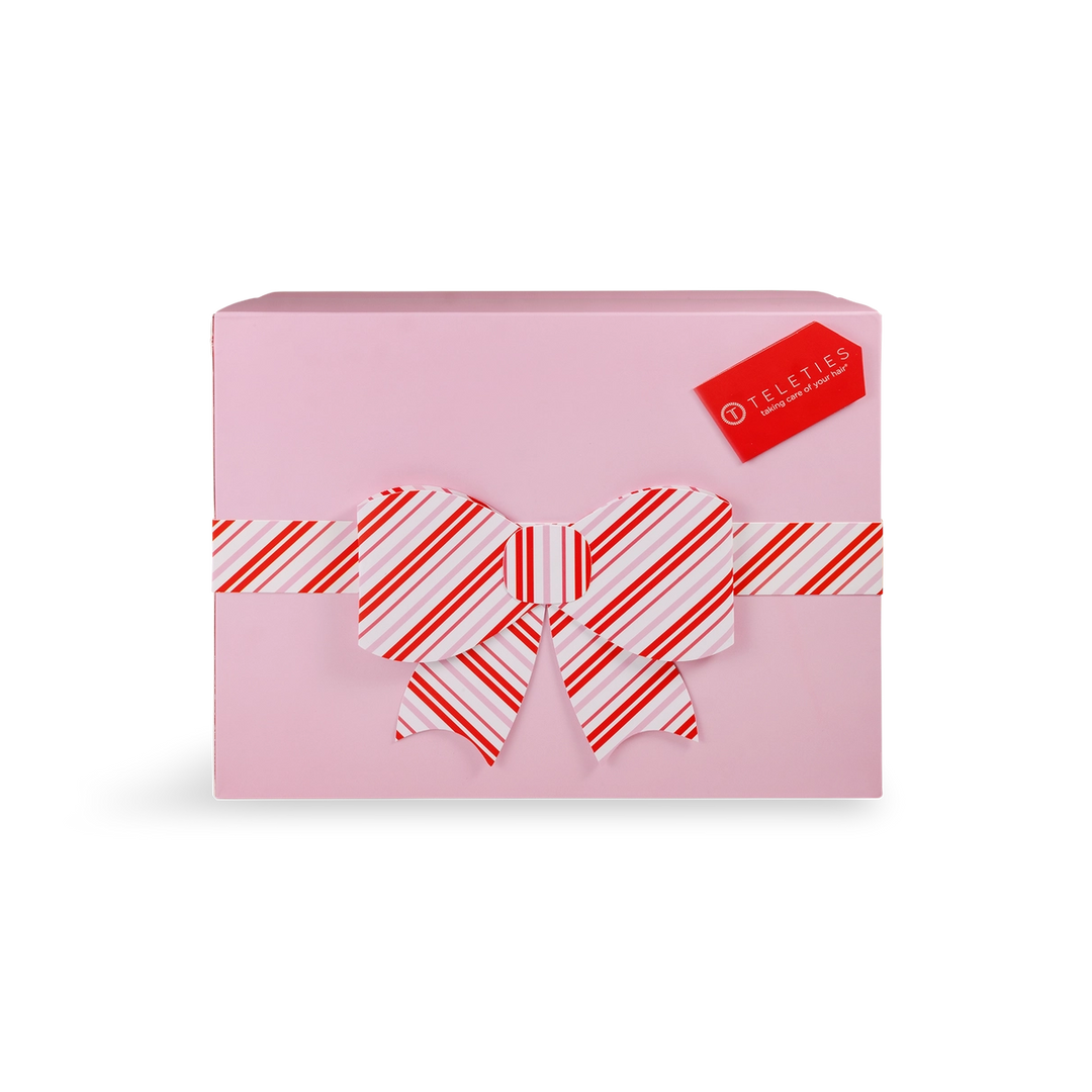 Pink gift box with a red and white striped bow on a white background