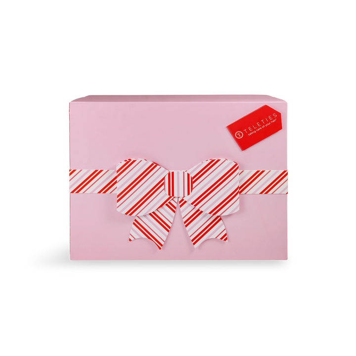 Pink gift box with a red and white striped bow on a white background