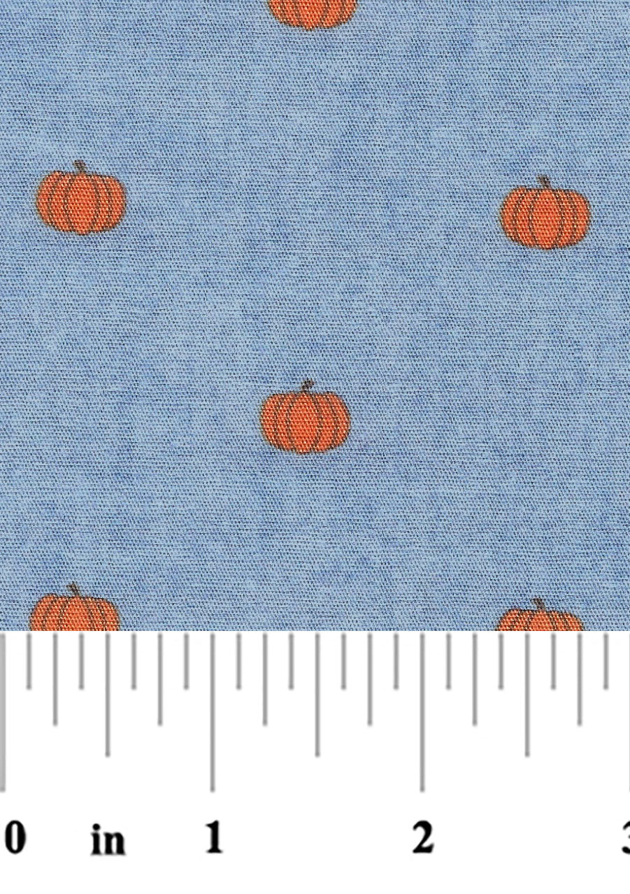 A fabric with a blue background and orange pumpkin designs, measured with a yardstick to be 60 inches wide.