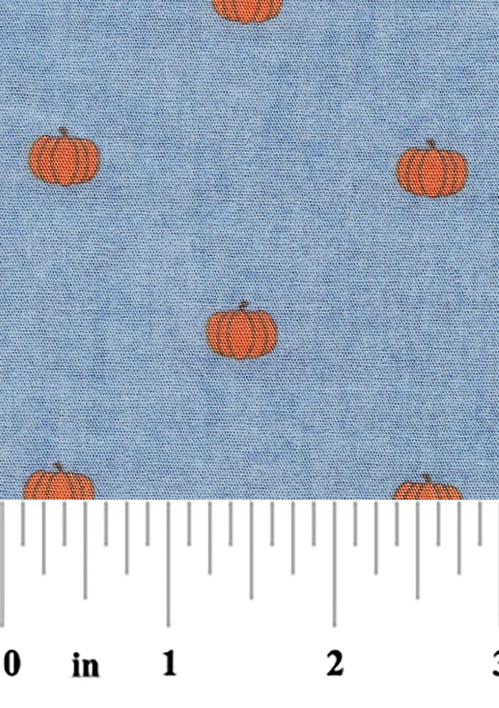 A fabric with a blue background and orange pumpkin designs, measured with a yardstick to be 60 inches wide.