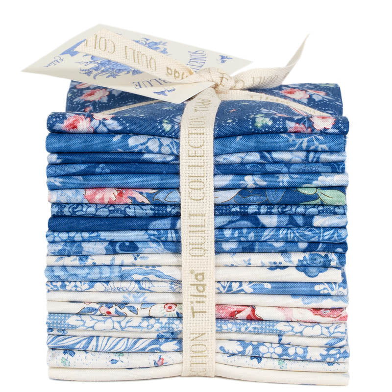 Stack of blue floral fabric bundles with Tilda label on a white background