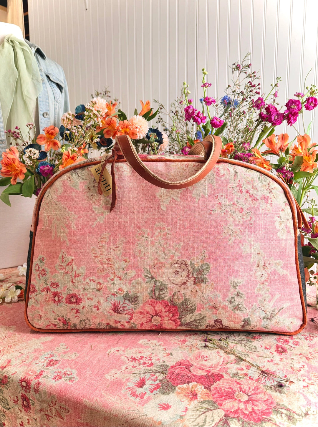 Floral-patterned handbag on a table with flowers in the background