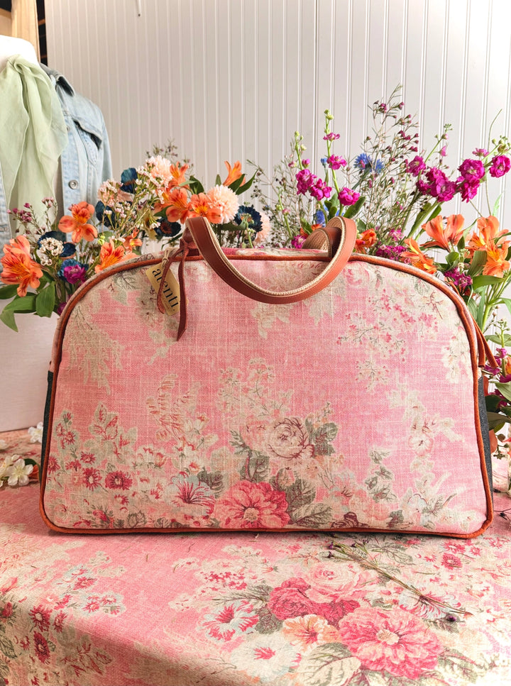 Floral-patterned handbag on a table with flowers in the background