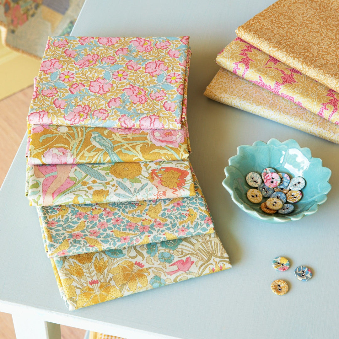 Stacks of fabric with floral patterns on a light blue surface.