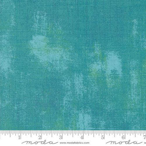 Textured teal fabric with a ruler at the bottom for scale, featuring the Moda Fabrics logo.