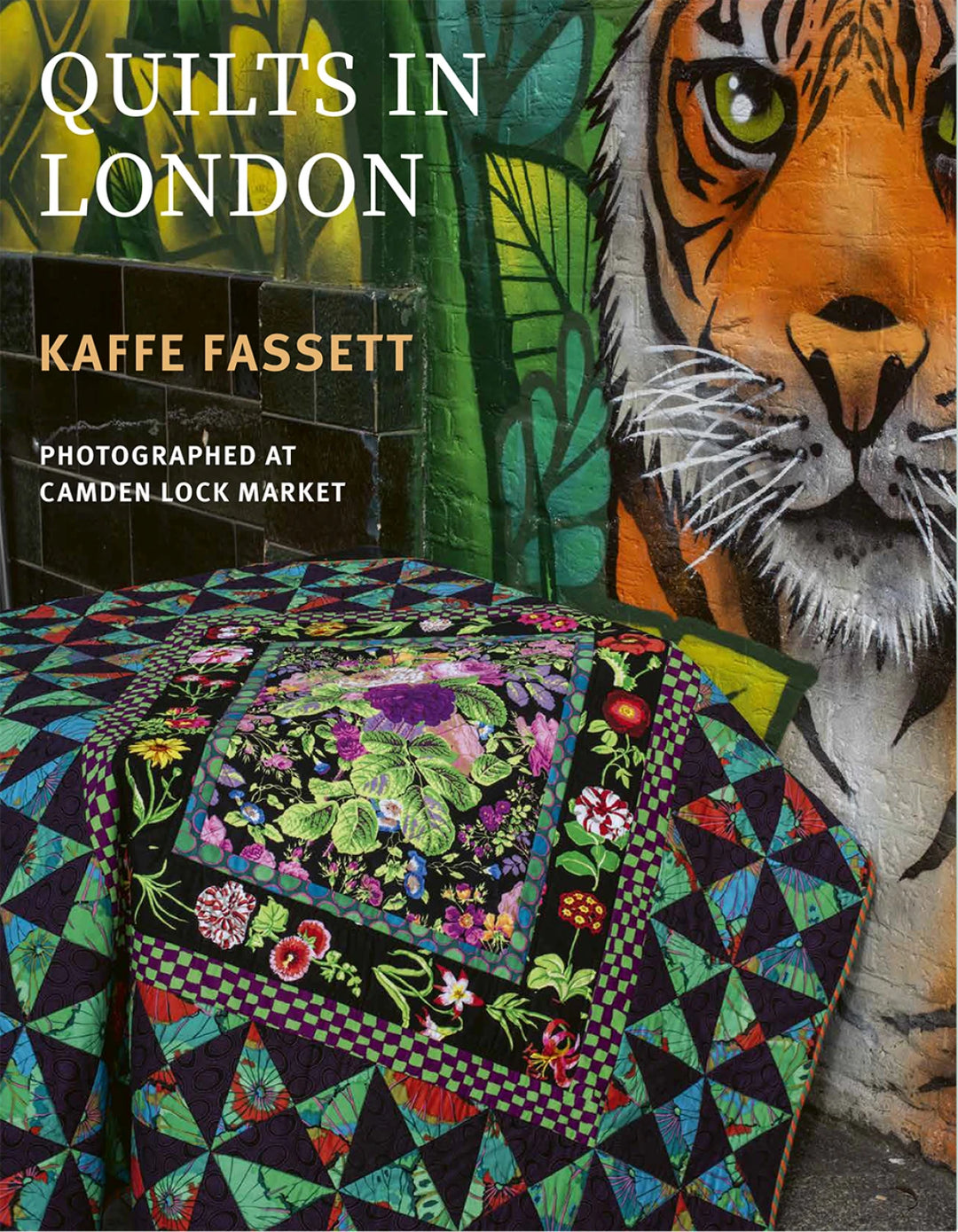 Quilt with floral patterns next to a tiger mural at Camden Lock Market, featuring Kaffe Fassett's work.