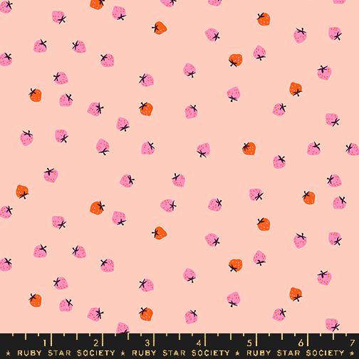 Red and pink mini strawberries on a pale peach background