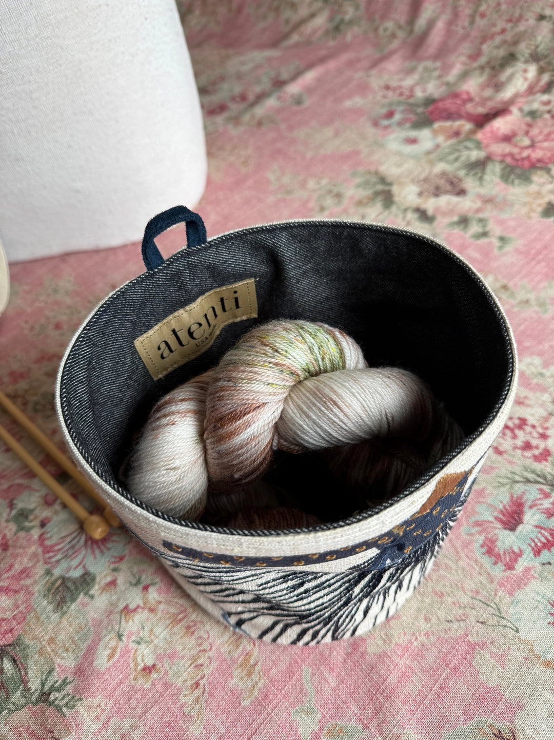 Yarn ball in a decorative container on a floral fabric background