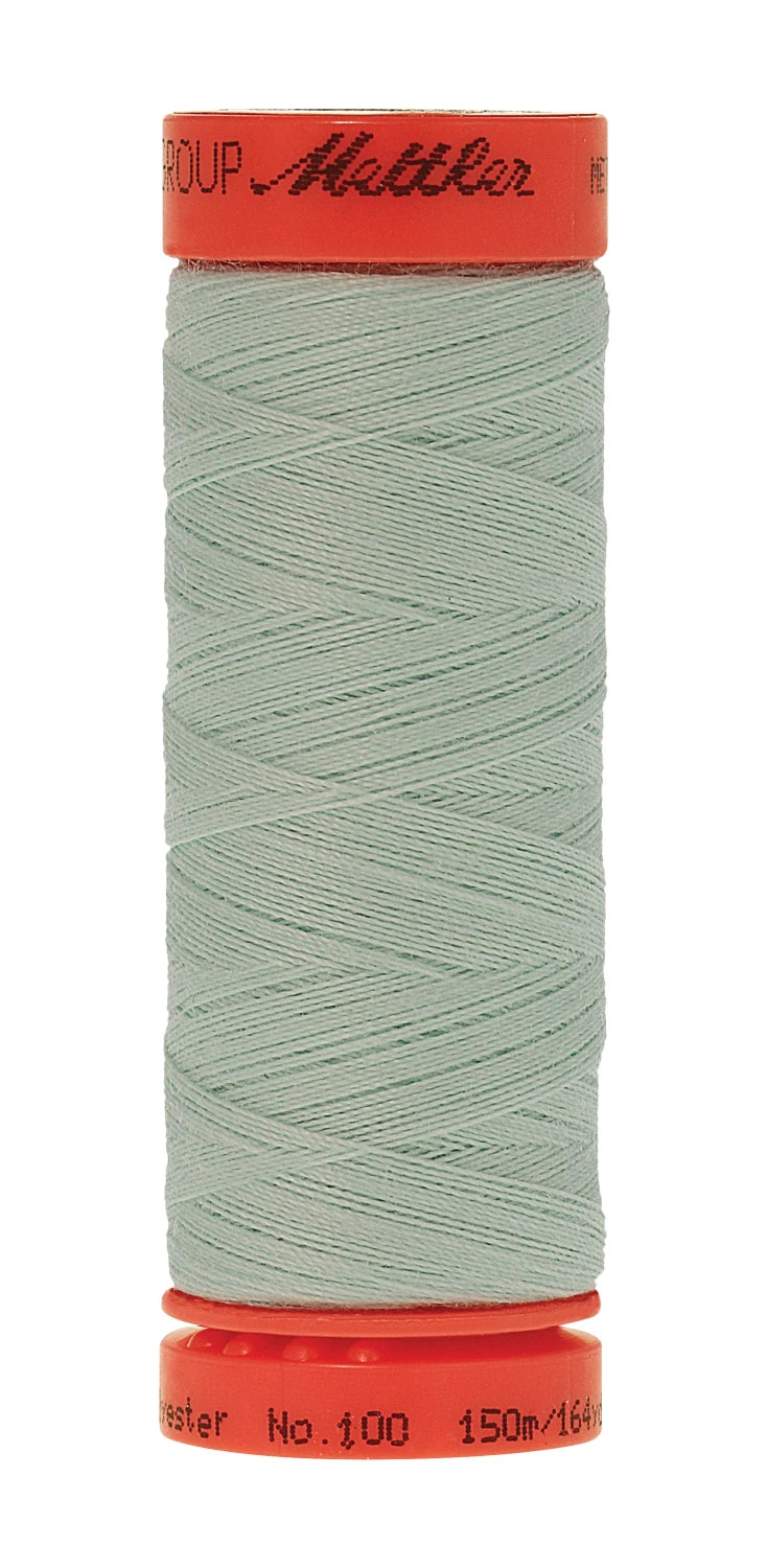 Spool of light green thread with red cap on a white background