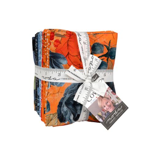 Stack of Coven fabric bundles with a ruler and Moda label on a white background