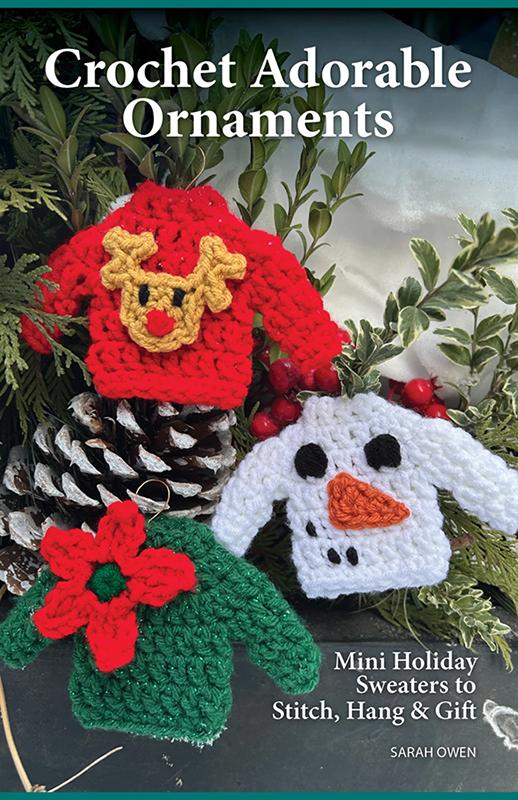 Crocheted ornaments including a reindeer, snowman, and penguin on a pine cone with greenery in the background.