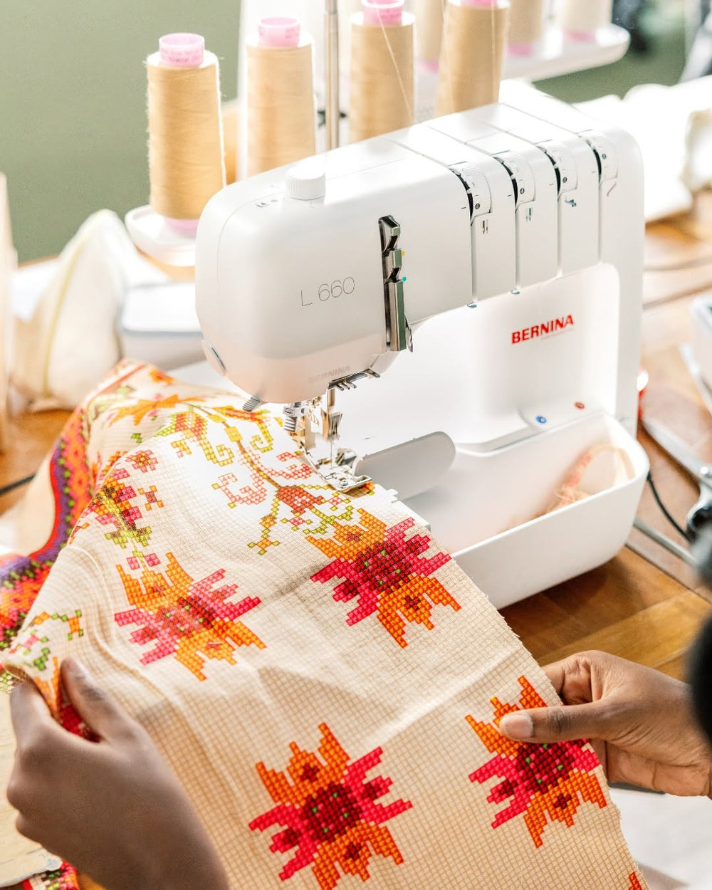 Sewing machine with a piece of fabric featuring floral patterns on a wooden table.