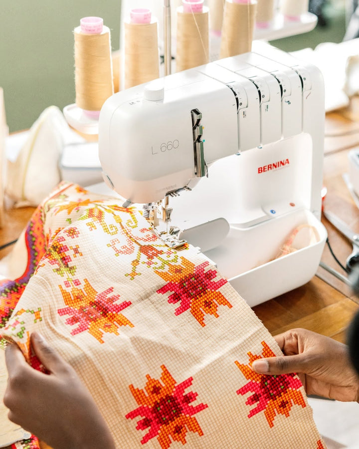 Sewing machine with a piece of fabric featuring floral patterns on a wooden table.