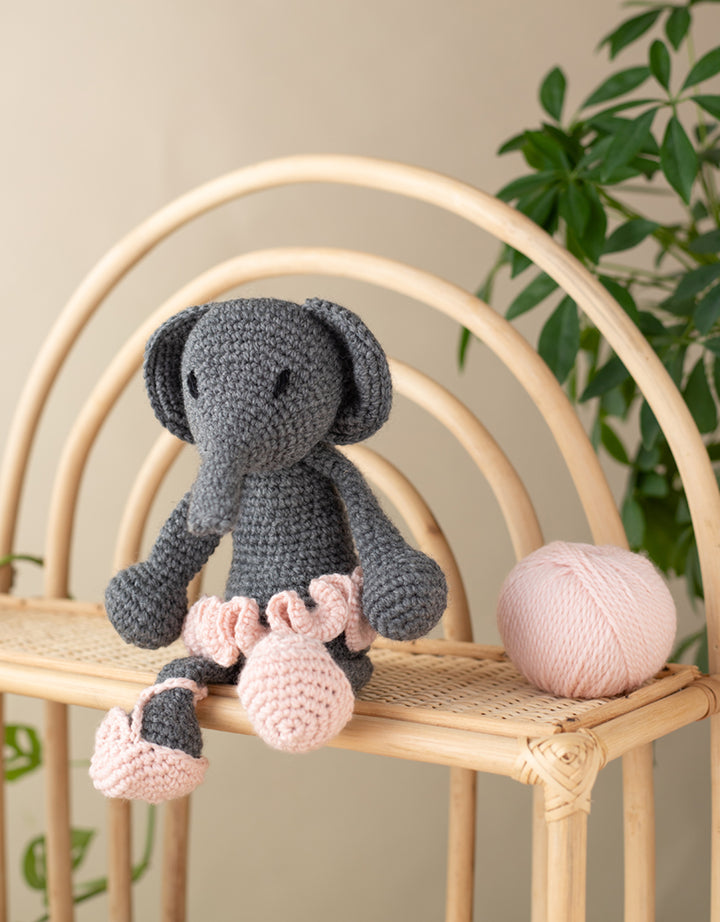 Bridget the Ballerina elephant sitting on a wooden rattan shelf