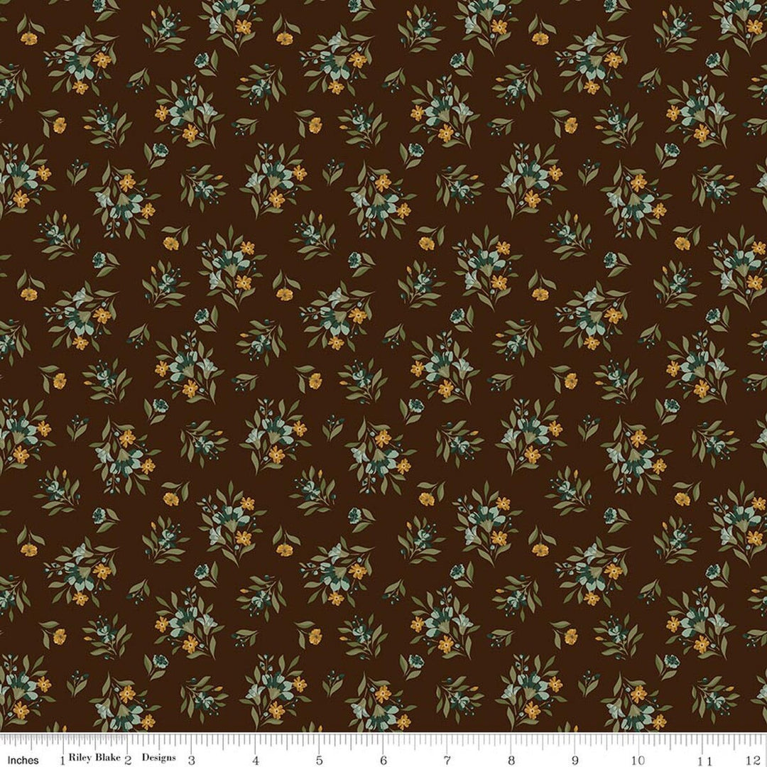This print features small sprigs of orange and blue flowers and leaves on a warm brown background. A white ruler strip appears along the bottom edge showing scale.
