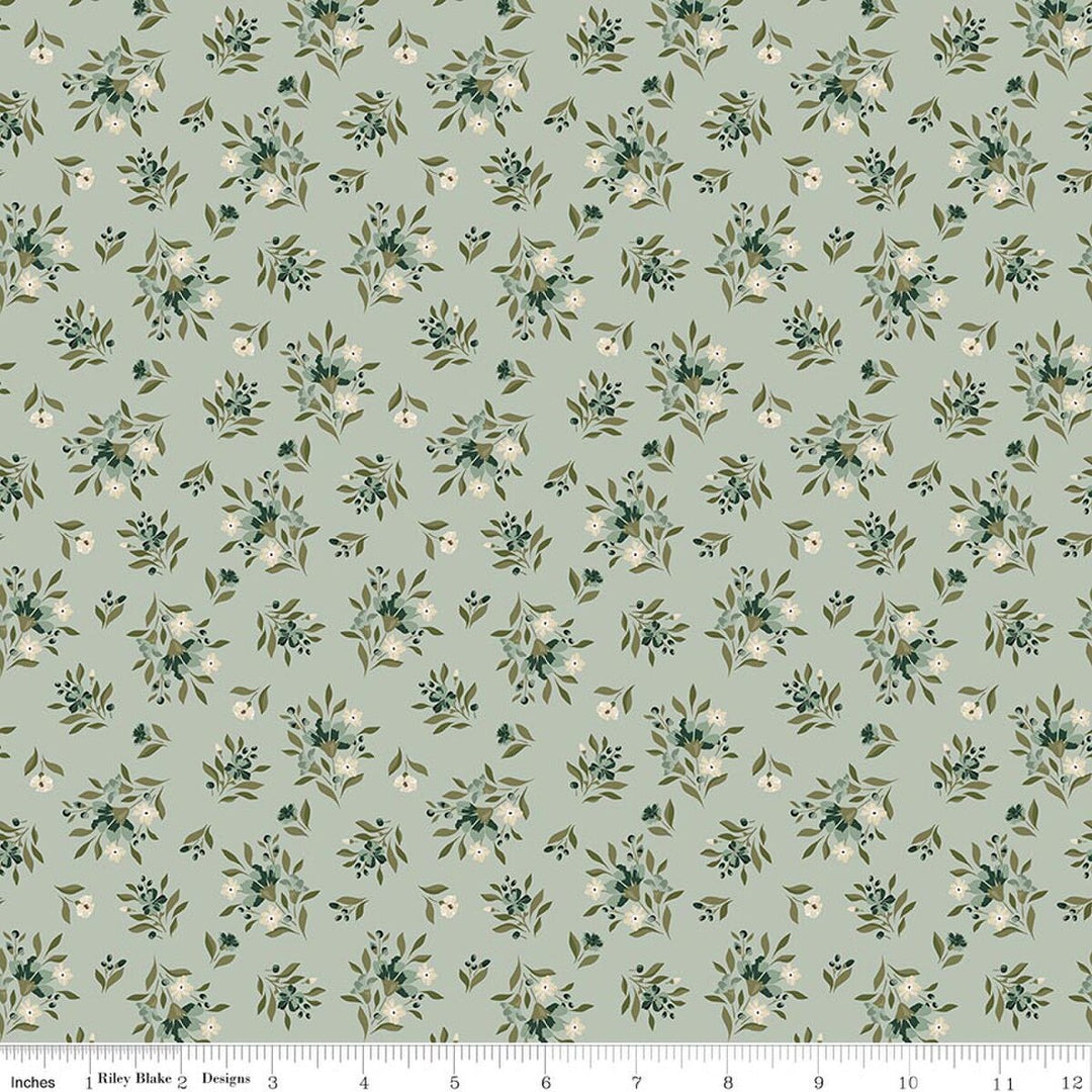 This print features small sprigs of white and blue flowers and leaves on a cool green background. A white ruler strip appears along the bottom edge showing scale.
