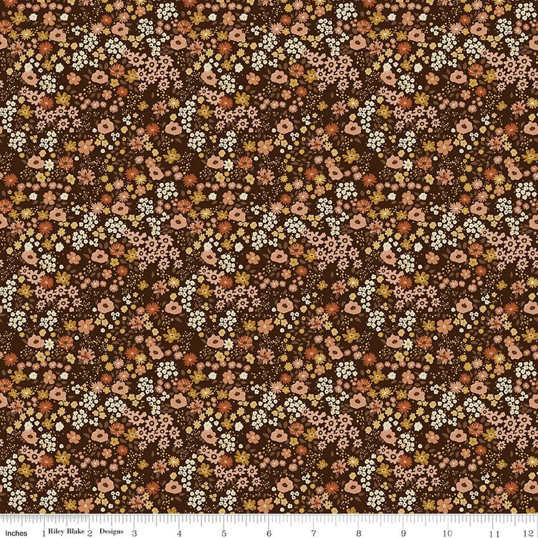 This print features small sprigs of rust, white, blush and dark yellow  flowers and leaves on a brown background. A white ruler strip appears along the bottom edge showing scale.