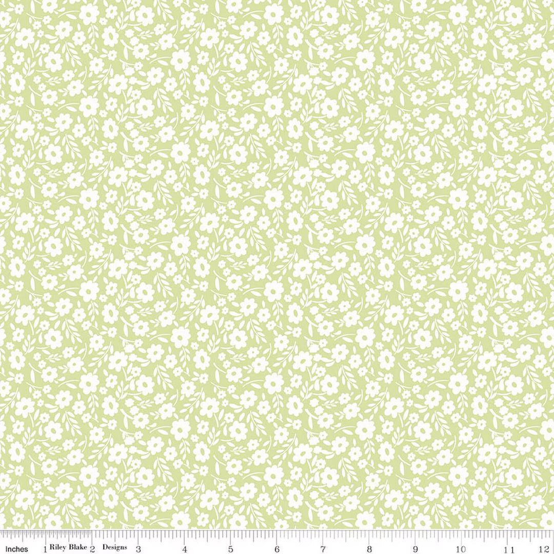 This print features a white sprigs of flowers on a green background. There is a ruler on the bottom for scale. 