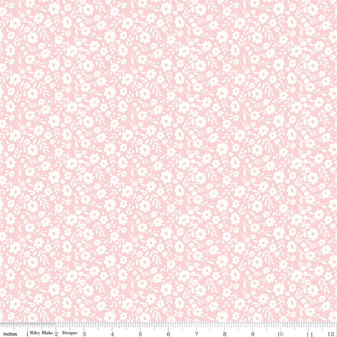 This print features a white sprigs of flowers on a pink background. There is a ruler on the bottom for scale. 