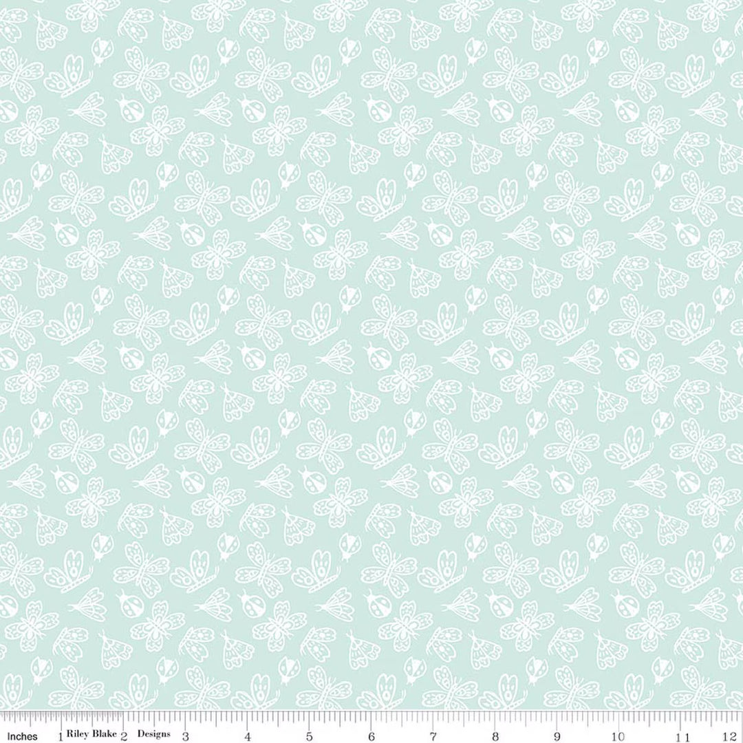 This print features outlined butterflies, moths, and lady bugs on an aqua background. There is a ruler along the bottom for scale. 
