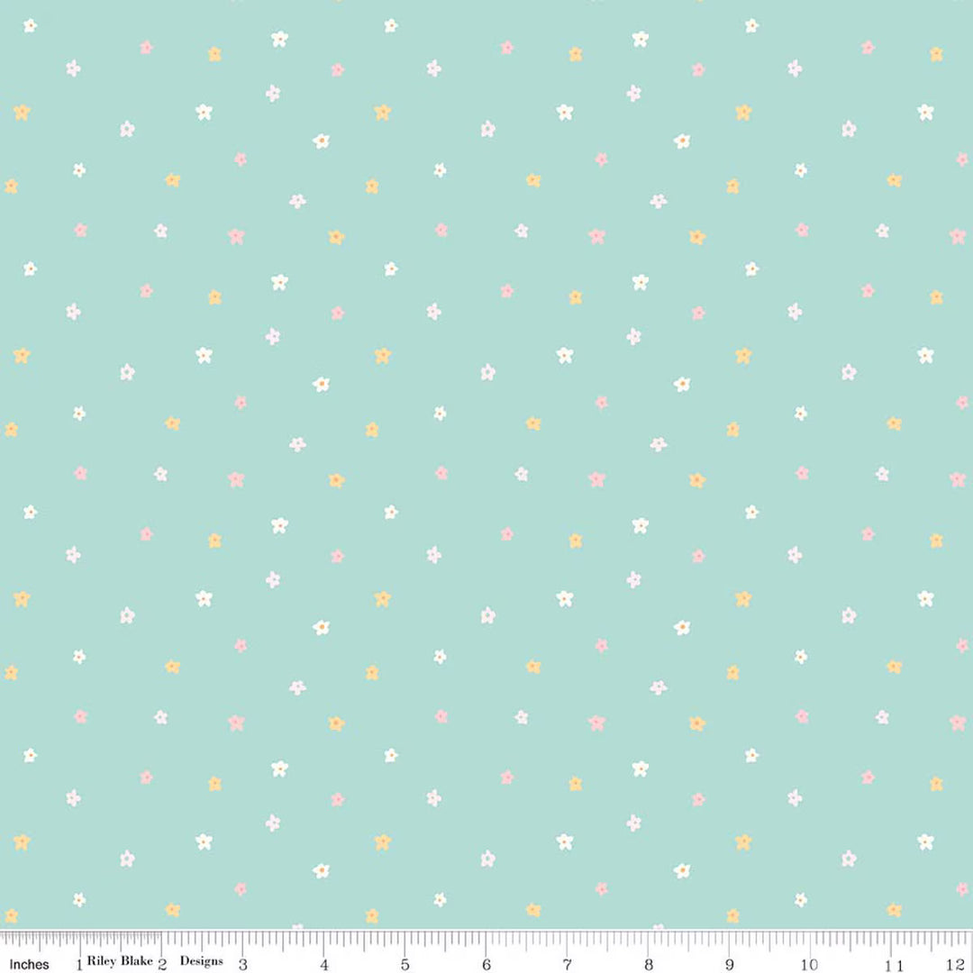 A repeating fabric pattern featuring scattered blossoms in pink, orange, and white on a light teal background, shown with a ruler along the bottom edge indicating scale.