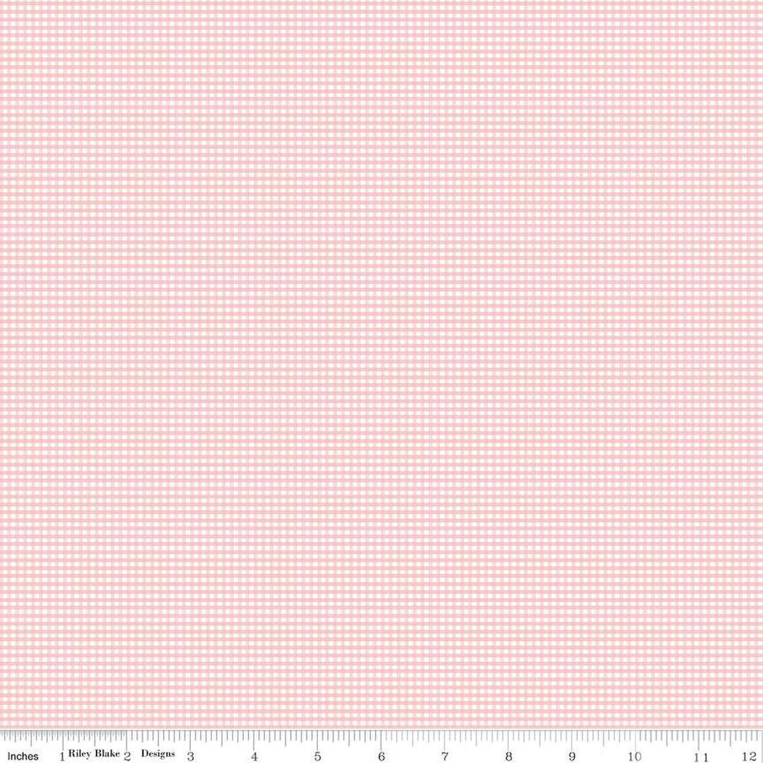 A close-up of a fabric pattern featuring a small pink and white gingham check, with a ruler scale at the bottom indicating inches and the brand 'Riley Blake Designs'.