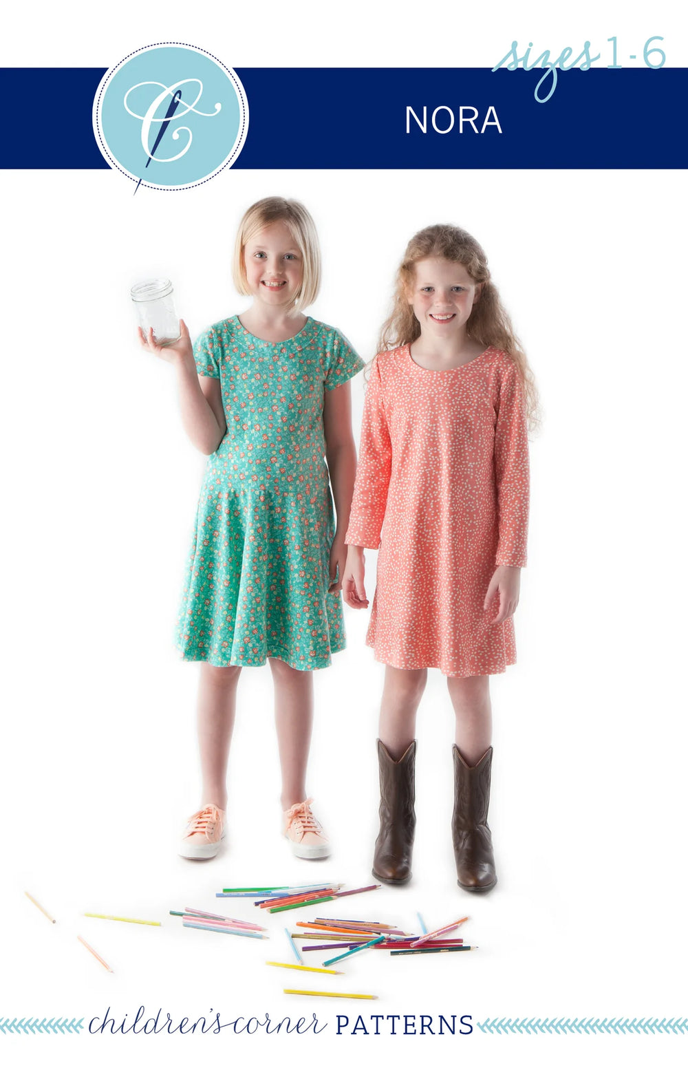 Two young girls wearing dresses with a pattern of colored pencils on the floor.