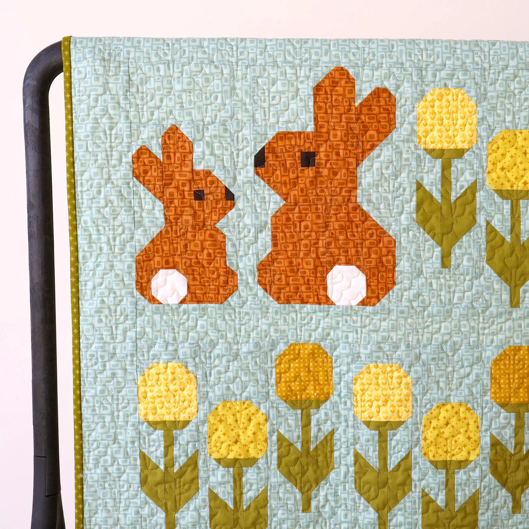 Quilt with bunny and flower pattern on a light blue background