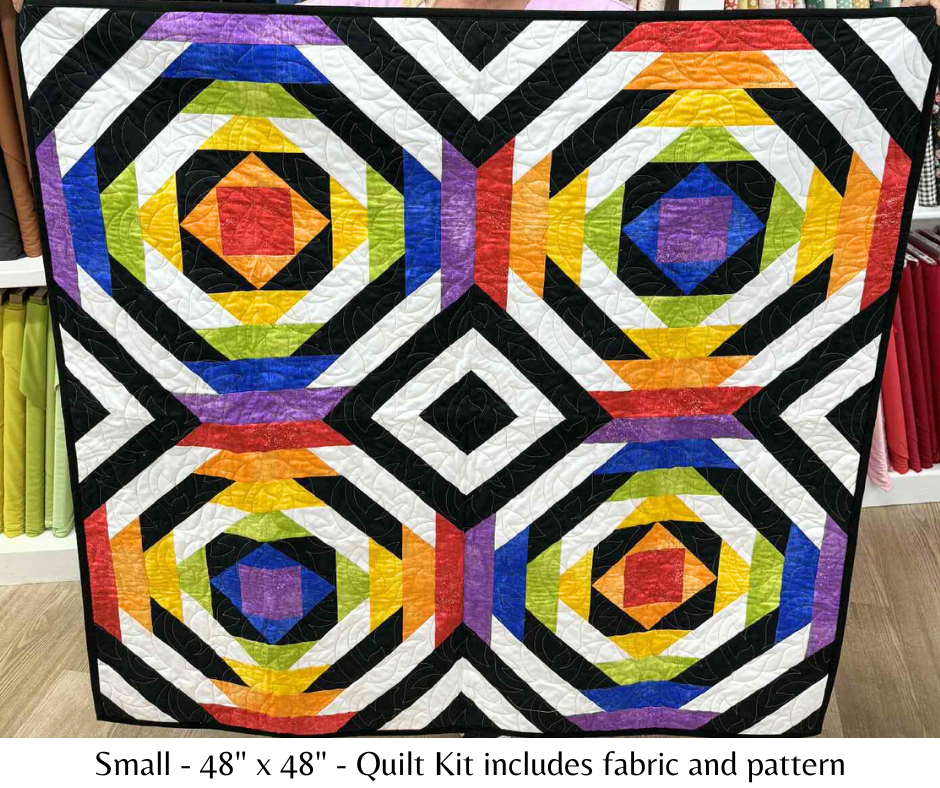 Colorful geometric quilt with rainbow patterns on a wooden floor.