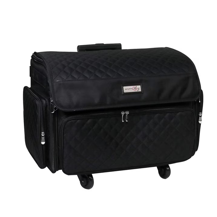 A black quilted rolling travel case with a top handle, four spinner wheels, a front zippered pocket, and a side zippered compartment, shown on a plain white background.