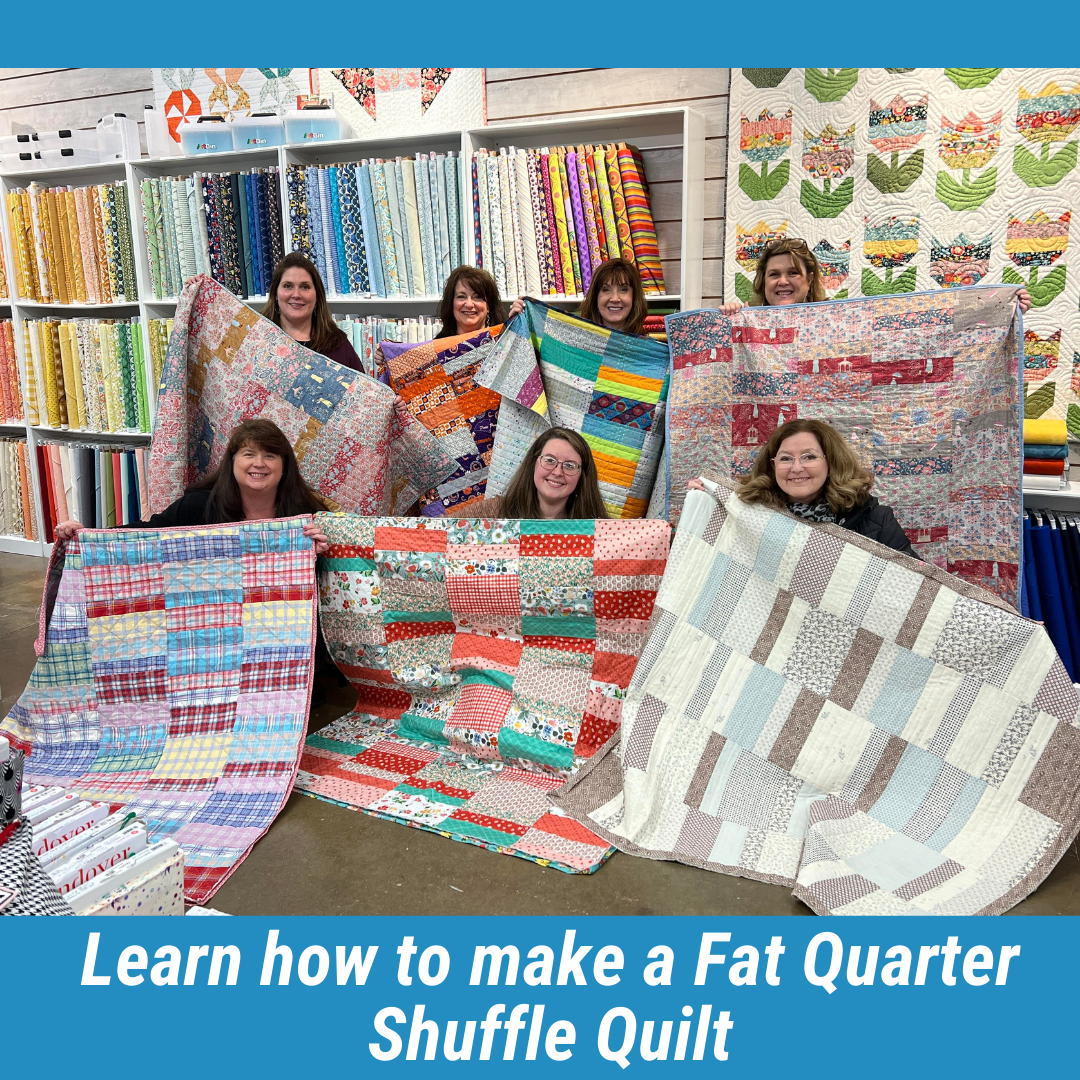 Seven women holding colorful quilts