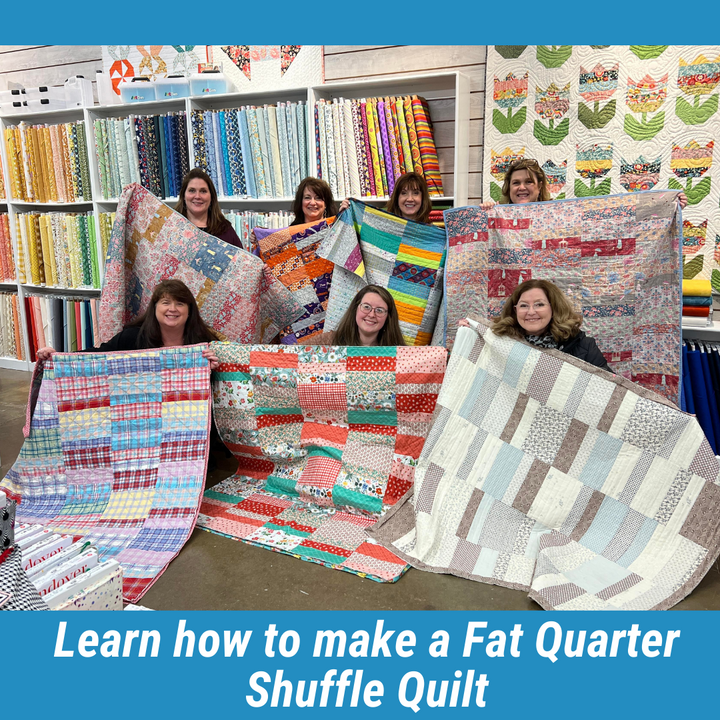 Seven women holding colorful quilts