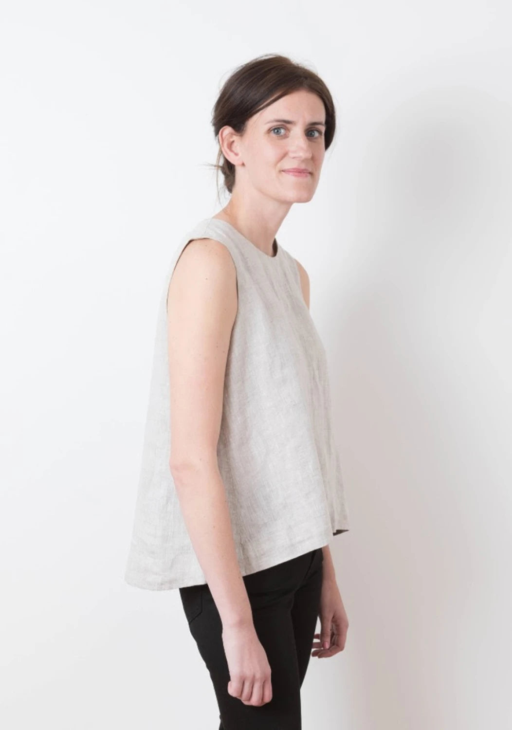 Woman wearing a light gray sleeveless top against a white background