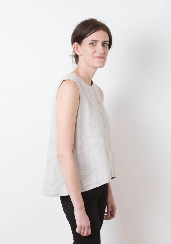 Woman wearing a light gray sleeveless top against a white background