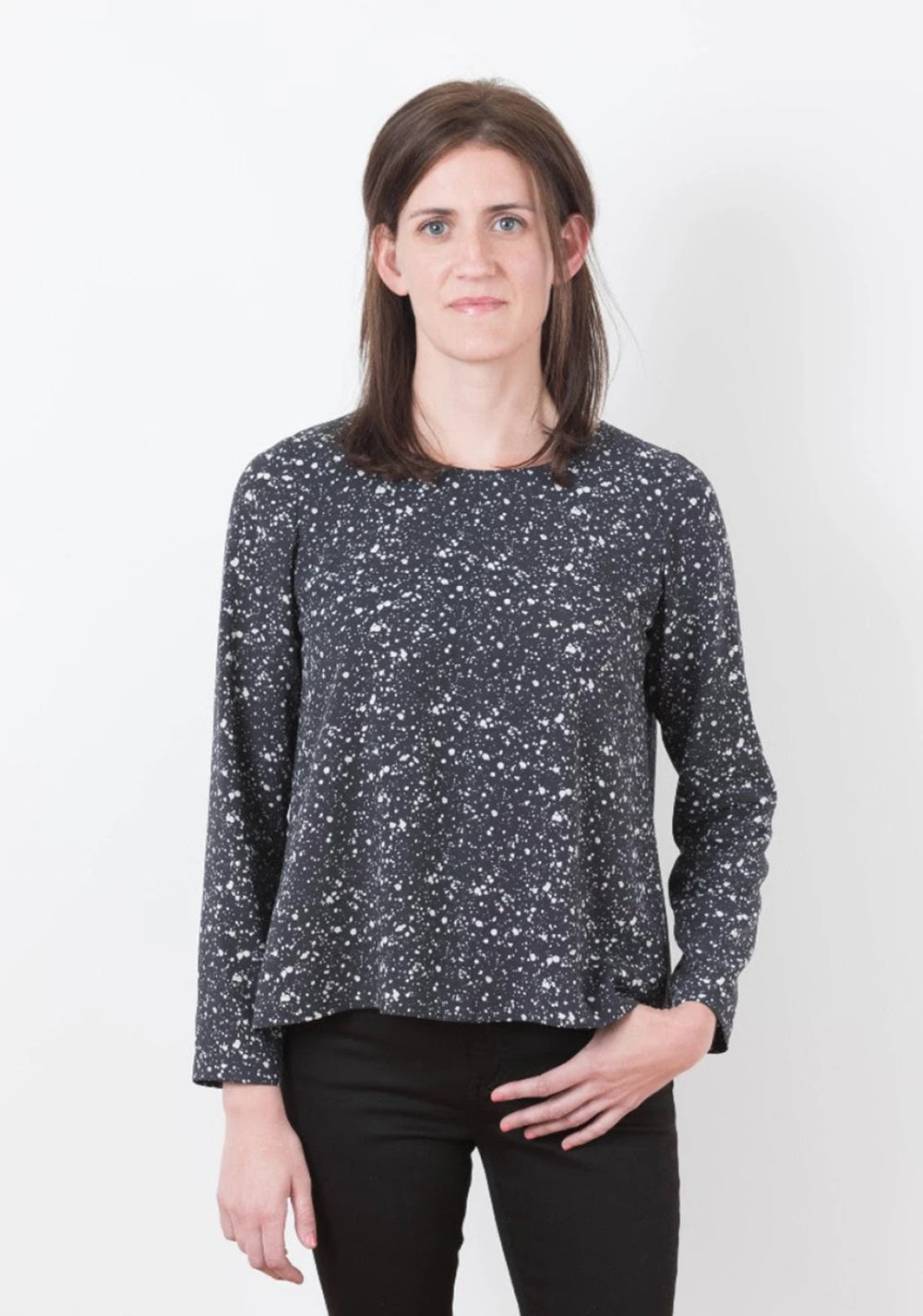 Woman wearing a black and white patterned long-sleeve top against a white background